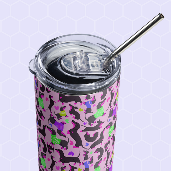 The Silly Sausages Stainless Steel Tumbler by My Favourite Colour is Rainbow features a vibrant design of abstract pink, purple, black, and green shapes on a light purple hexagonal grid. It comes with a clear lid and metal straw for reusable convenience.