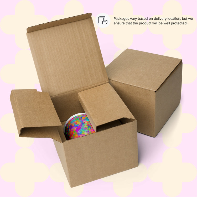 Two cardboard boxes, one revealing a colourful Splotches and Crosses Mug from My Favourite Colour is Rainbow.  There is a text overlay noting that packaging varies but will ensure protection.