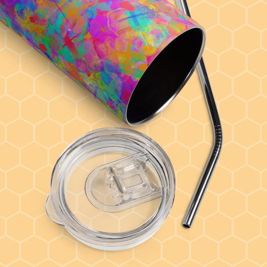 The Splotches and Crosses Stainless Steel Tumbler by My Favourite Colour is Rainbow, featuring a clear removable lid and metal straw, rests elegantly on a yellow honeycomb-patterned background.