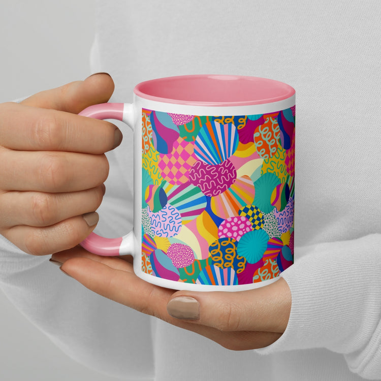 A person holding the Squiggs and Stripes Mug by My Favourite Colour is Rainbow, featuring a vibrant abstract pattern with colourful shapes and lines. The mug has a pink interior and handle.