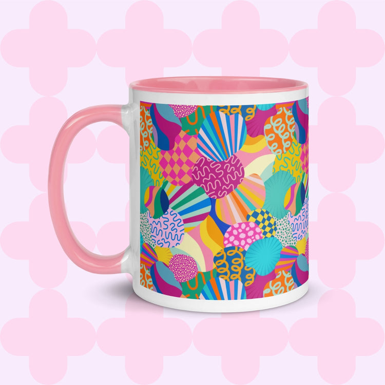 The Squiggs and Stripes Mug by My Favourite Colour is Rainbow features a white base with a vibrant abstract design of shapes and swirls in pink, yellow, blue, and green. A pink handle and interior adds contrast.