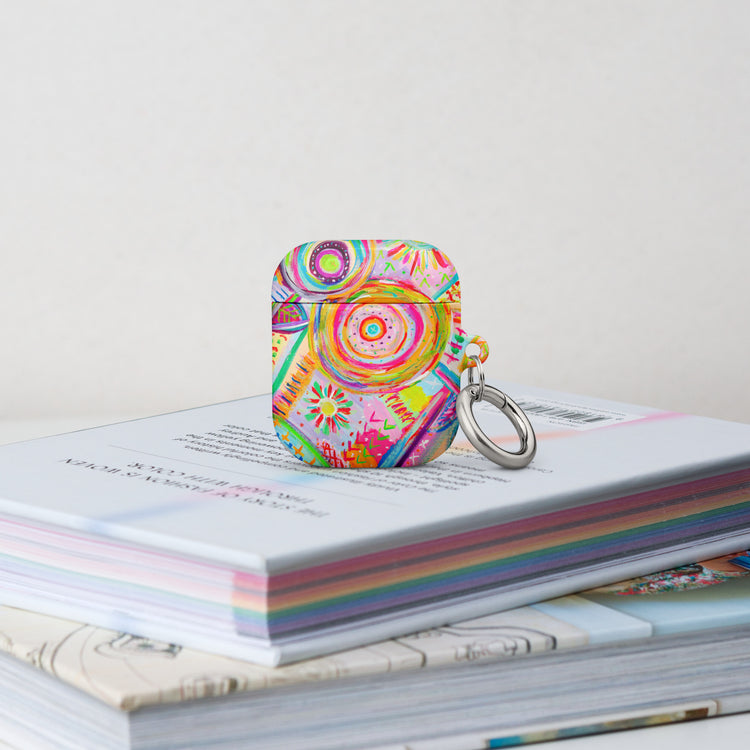 The Summer Sorbet Airpods Gen 1 Case stands on a stack of books.  It features a colourful abstract design with swirls, flowers, and geometric shapes in bright hues. 