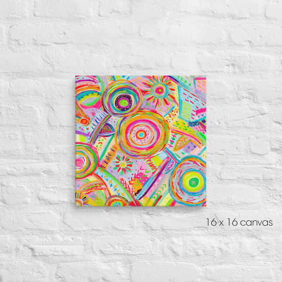 A vibrant 16x16-inch Summer Sorbet canvas by My Favourite Colour is Rainbow, featuring abstract circular and geometric patterns in pink, green, orange, and yellow, is mounted on a textured white brick wall.