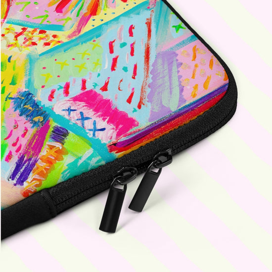 A close up of the Summer Sorbet Laptop Sleeve by My Favourite Colour is Rainbow shows the colourful design with bright pink, blue, and green abstract patterns.  It includes a black padded zipper binding with dual pull tabs for added convenience.  The print is on only one side of the laptop sleeve, the other side is black.   It is shown on a pastel background.