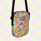 The Summer Sorbet Mini Crossbody Bag by My Favourite Colour is Rainbow boasts a vibrant abstract pattern with swirling pink, green, orange, and blue designs. It features adjustable black straps against a pastel pink and light green checkered backdrop.