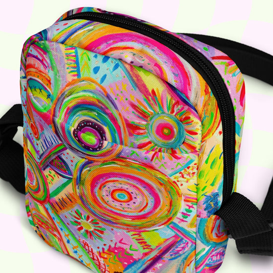 The Summer Sorbet Mini Crossbody Bag from My Favourite Colour is Rainbow showcases a colorful abstract circular and geometric print in vibrant pink, orange, yellow, and green hues. It features black zippers and adjustable straps for added comfort.