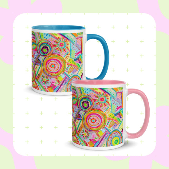 Two Summer Sorbet Mugs from My Favourite Colour is Rainbow, featuring my Summer Sorbet painting: vibrant abstract circular and geometric patterns.  One mug has a blue handle and interior, the other pink.  The mugs are set against a pastel background with green crosses and shapes.