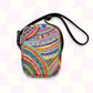 The Rainbow Connection Mini Crossbody Bag by My Favourite Colour is Rainbow features a rainbow-patterned fabric with stripes, dots, and zigzags, a black adjustable strap, and zip closure on a light checkerboard background.