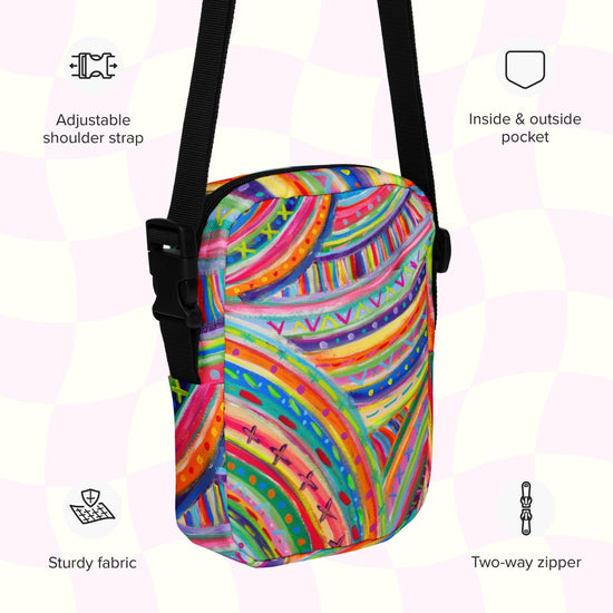 An infographic highlighting features of The Rainbow Connection Mini Crossbody Bag by My Favourite Colour is Rainbow: adjustable shoulder strap, inside and outside pocket, sturdy canvas fabric and a two-way zipper. 