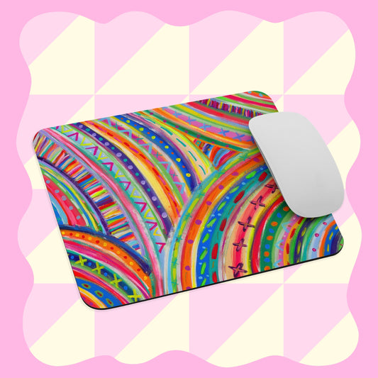 A white computer mouse sits on the Rainbow Connection Mouse Pad by My Favourite Colour is Rainbow, which features vibrant swirling rainbow patterns, geometric shapes, and a pink checkerboard background with wavy edges.