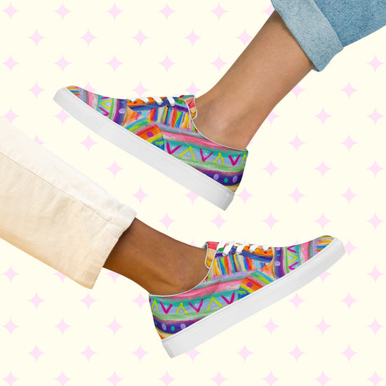 Two people wearing The Rainbow Connection Canvas Sneakers from My Favourite Colour is Rainbow are positioned soles together against a pale background with small pink stars, showcasing vibrant geometric designs in purple, blue, green, and orange—a true rainbow shoes adventure!.