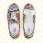 The Rainbow Connection Canvas Sneakers by My Favourite Colour is Rainbow feature vibrant geometric patterns in pink, blue, green, yellow, and orange on a pastel backdrop with faint pink starbursts. One shoe is shows the size label on the underside of the tongue.