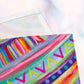 A detailed view of The Rainbow Connection Cloth Napkin Set of 4 by My Favourite Colour is Rainbow, showcasing vibrant pink, turquoise, and purple stripes with yellow V-shapes and colorful dots. The soft pastel background enhances the lively patterns.