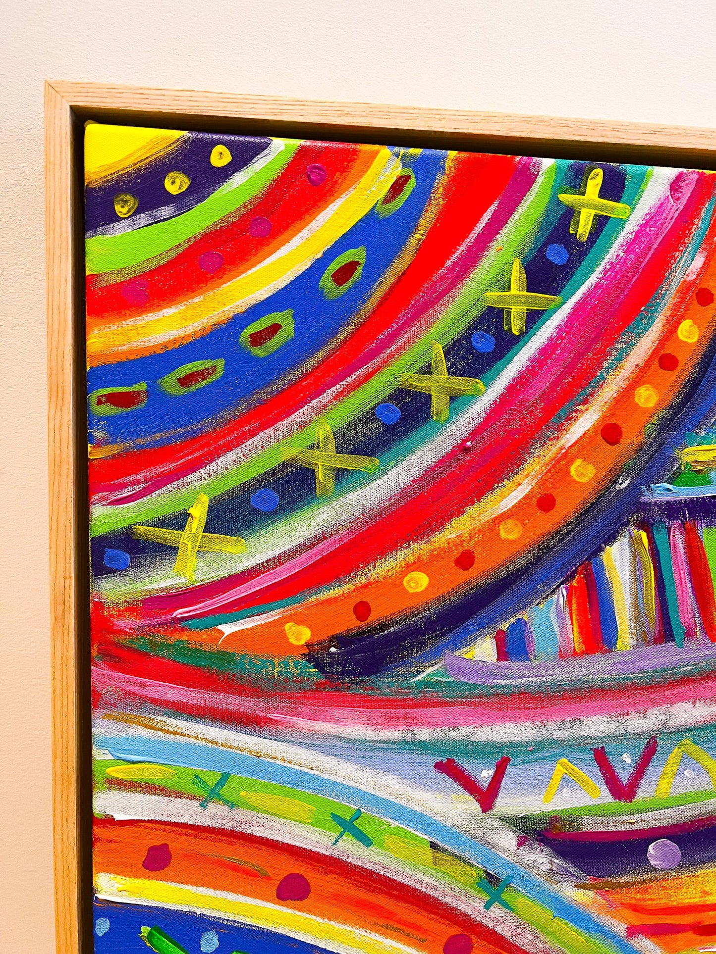 Close-up of The Rainbow Connection, an acrylic painting with red, orange, purple, and blue waves plus vibrant green and yellow X shapes. Professionally framed in light wood from My Stores The Rainbow Connection Framed Original Painting collection.