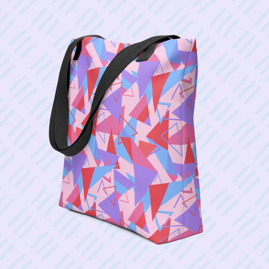 The Tri the Angle Tote Bag by My Favourite Colour is Rainbow features red, purple, blue, and pink triangle patterns with a black handle. 