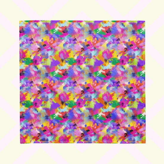 The Watercolour Rainbow Bandana by My Favourite Colour is Rainbow features a vibrant abstract design with blue, green, pink, orange, and purple splashes. It is shown against a pastel background.