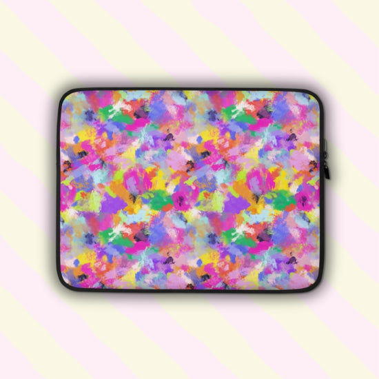 The Watercolour Rainbow Laptop Sleeve by My Favourite Colour is Rainbow features a vibrant abstract pattern with pink, purple, blue, yellow, and green splashes.  The print is on only one side of the laptop sleeve, the other side is black.
