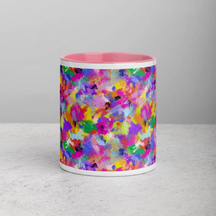 Front view of a Watercolour Rainbow Mug by My Favourite Colour is Rainbow, featuring a vibrant abstract design with splashes of pink, yellow, blue, and green on the exterior and a pink interior, set against a light grey stone surface.