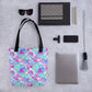 The Pastel Rainbow Tote Bag by My Favourite Colour is Rainbow is the centerpiece of a flat lay, surrounded by sunglasses, notebooks, pens, a phone, a camera lens attachment, a closed laptop, a woven pouch, and a tassel keychain.