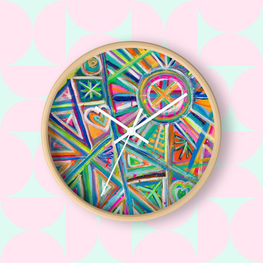 The Geometric Rainbow Wall Clock by My Favourite Colour is Rainbow adds vibrant décor to a space with its colourful abstract geometric patterns in blues, greens, oranges, and pinks. It has a light wood frame and white hands.  The clock sits above a wooden surface with a small potted succulent against a white wall.